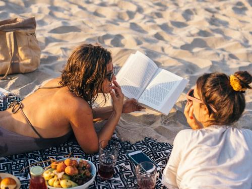 two people sitting on the beach reading a book at Tombo Beach in Guarujá