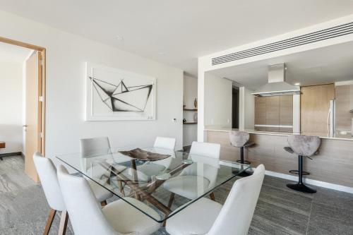 a dining room with a glass table and white chairs at Luxury Condo of 4 Bedrooms in Cancún