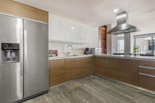 a kitchen with wooden cabinets and a stainless steel refrigerator at Luxury Condo of 4 Bedrooms in Cancún