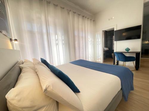 a bedroom with a large white bed with blue pillows at Duomo Rooms - Manfredi Homes&Villas in Manfredonia
