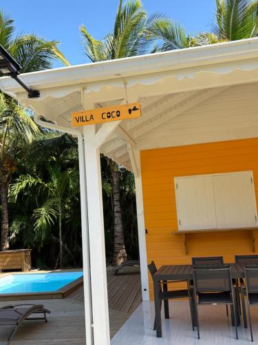 a patio with a table and chairs and a pool at Le Paradis de la Guadeloupe in Pointe-Noire