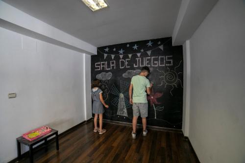 two people are writing on a wall in a room at Villa Turistica de Bubion in Bubión