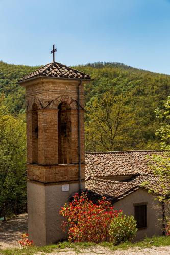 a brick tower with a cross on top of a building at Tenuta Borgo Santa Cecilia in Gubbio