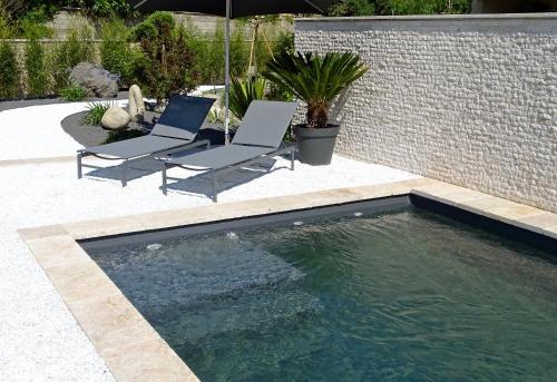 a swimming pool with two chairs and an umbrella at Maison du Lac in Les Angles Gard