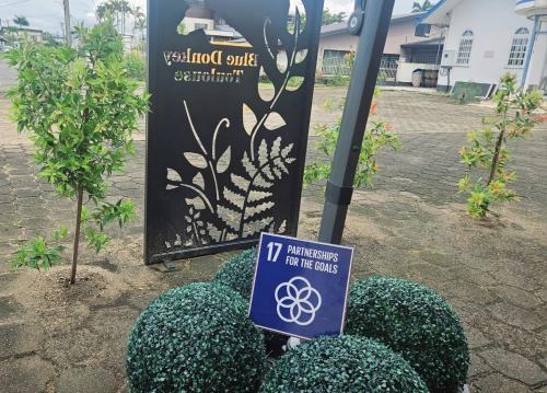 a sign in front of a sign with bushes at The Blue Donkey in Paramaribo
