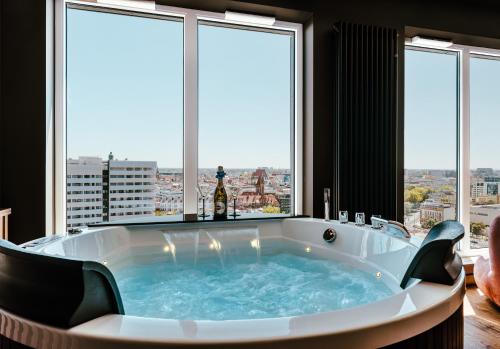 a large bath tub in a room with windows at SAUNA JACUZZI River View QUORUM Apartment in Wrocław