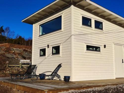 a house with two chairs on a wooden deck at New villa, 45sqm, 2 bedrooms, loft, 80m from beach, fantastic views & very quiet area in Onsala