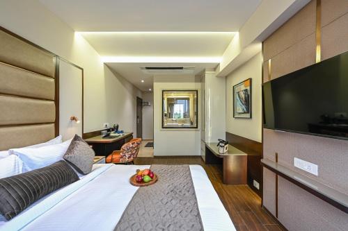 a hotel room with a bed with a bowl of fruit on it at Hotel Grand Girdhar Premier in Indore