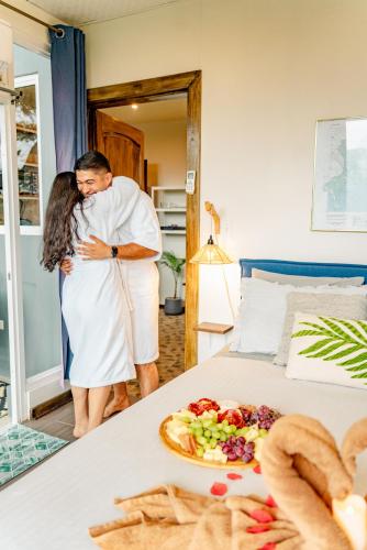 a man and woman standing next to a bed with a plate of food at Casa Ejecutiva Boquete in Boquete