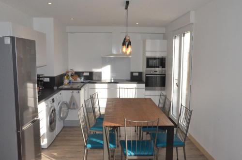 une cuisine avec une table et des chaises et une cuisine avec des appareils blancs dans l'établissement Maison bord de mer - Baie de Douarnenez - Piscine couverte, à PloÃ©ven