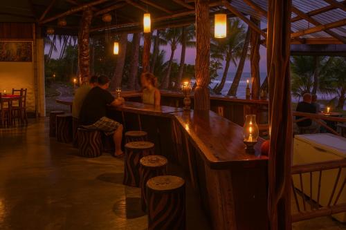 a couple sitting at a bar at a resort at La Leona Eco Lodge in Carate