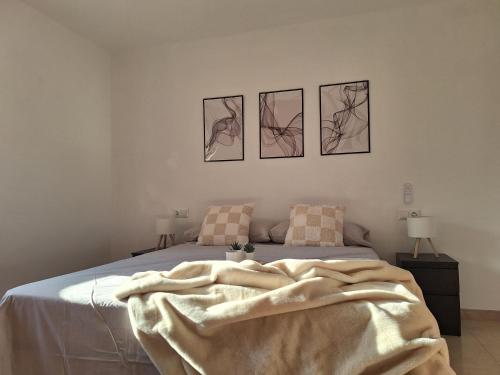 a bedroom with a bed with four pictures on the wall at La Karina in Denia
