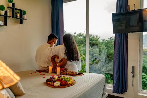 a man and woman sitting on a bed with a plate of fruit at Casa Ejecutiva Boquete in Boquete