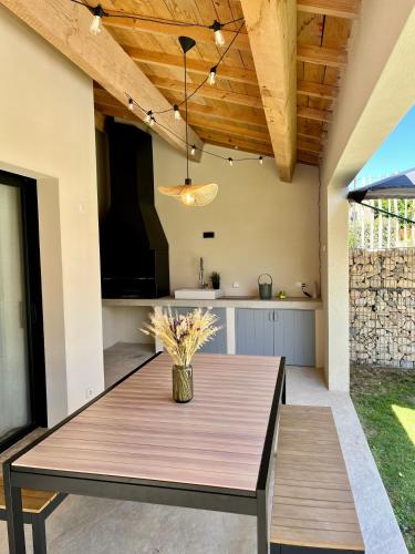 - une table en bois avec un vase de fleurs sur la terrasse dans l'établissement Villa Nova Ventoux, à Malaucène