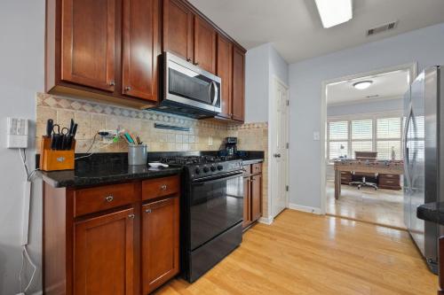 a kitchen with wooden cabinets and a stove top oven at Relaxing 3BR Duplex Home w/ Pool & Patio in Buford