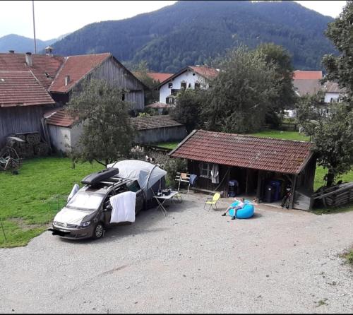 un coche aparcado frente a una casa con una tienda de campaña en Biohof Dimper - Stellplatz, Campingplatz, en Saulgrub