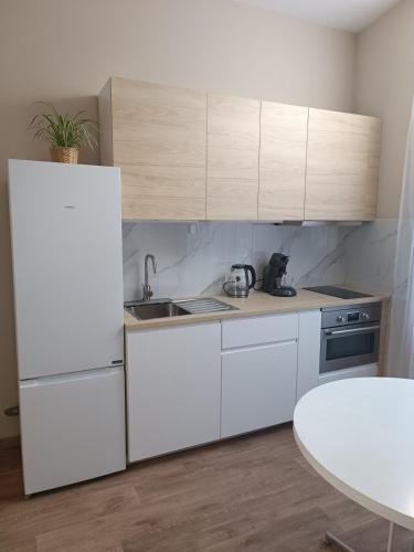 cocina con armarios blancos, fregadero y mesa en AppartCosy, en Mellet