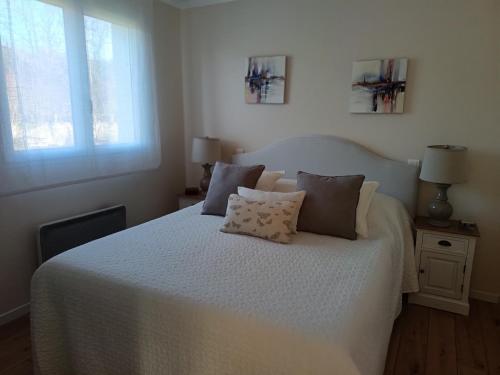 a bedroom with a white bed with two pillows at Le Charme des Bastides in Castelnau-de-Montmiral