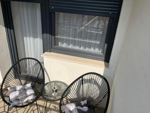 two chairs sitting on a balcony next to a window at Apartman Relax in Arandjelovac