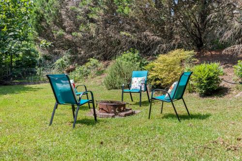 three chairs sitting in the grass next to a fire pit at Pool and Patio, 8 minutes from Mall of Georgia! in Buford