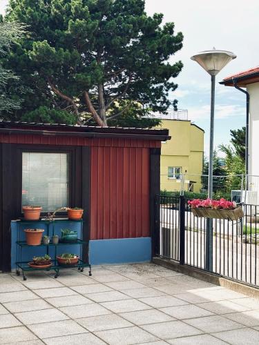 a red building with shelves next to a fence at Sunlit Apartment with Garden, Next to Station, Vienna in Vösendorf