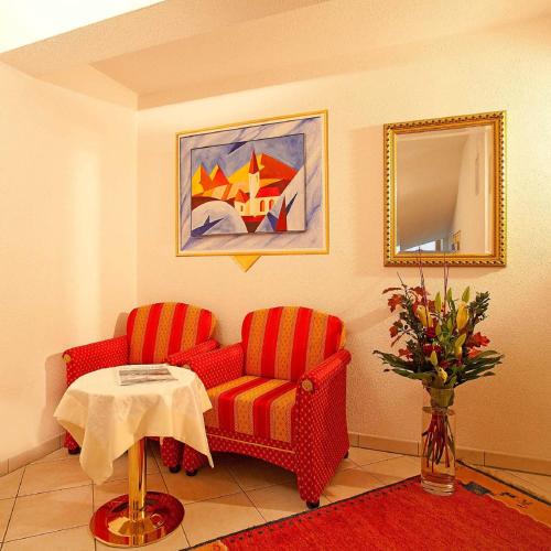 a living room with two red chairs and a table at Ferienresidenz La Vita in Längenfeld