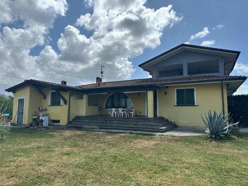 a yellow house with a porch with chairs on it at La Paulonia Country House in Capezzano Pianore,