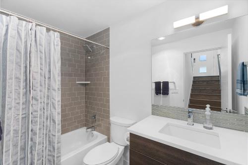 a bathroom with a toilet and a sink and a mirror at Golden Gardens Getaway-Walk to Beach & Waterfront in Seattle
