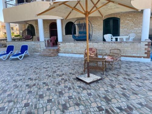 a patio with a table and chairs and an umbrella at First Row Sea-Front Chalets Media Village in Marsa Matruh
