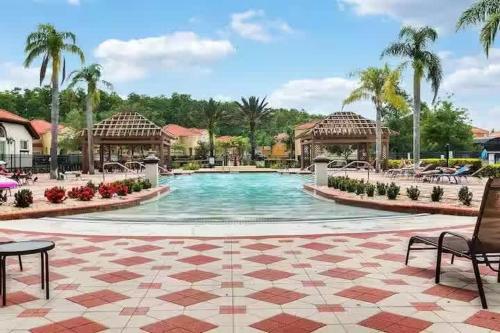 une piscine dans un complexe hôtelier avec des chaises et des palmiers dans l'établissement Charming 3BR Resort Townhome with Private Pool near Disney, à Kissimmee