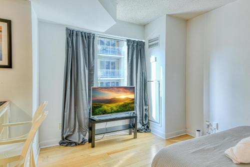 a bedroom with a flat screen tv in front of a window at RivetStays - The Pantages Suite in Toronto