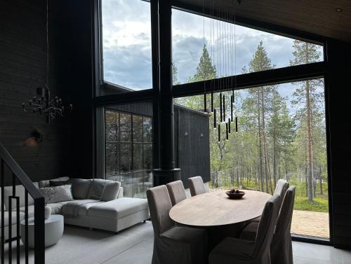 a living room with a table and a couch at Black Villa, Aurora View Bath & Sauna, Private Design Villa in Lapland in Kolari