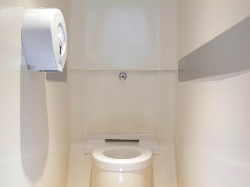 une salle de bains blanche avec toilettes et distributeur de papier dans l'établissement Hotel First Eco Dieppe, à Dieppe