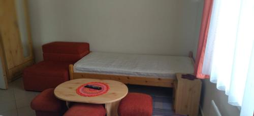 a room with a bed and a table and a chair at KOÓS VENDÉGHÁZ in Uppony