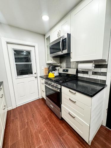 a kitchen with white cabinets and a stove top oven at Emperors Pool House in Jacksonville