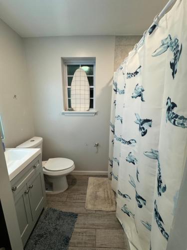 a bathroom with a toilet and a shower curtain at Emperors Pool House in Jacksonville