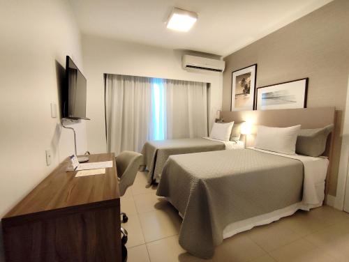 a hotel room with two beds and a television at Matiz Multi Suites in Duque de Caxias