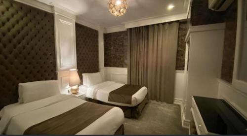a hotel room with two beds and a tub at إيلاف الدمام للوحدات السكنية المخدومة in Dammam