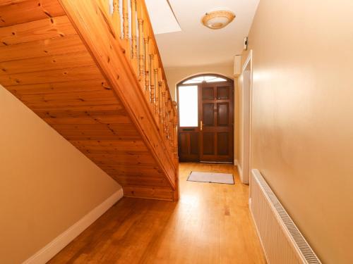 a hallway with a wooden staircase with a door at 51 Woodview Park in Tralee