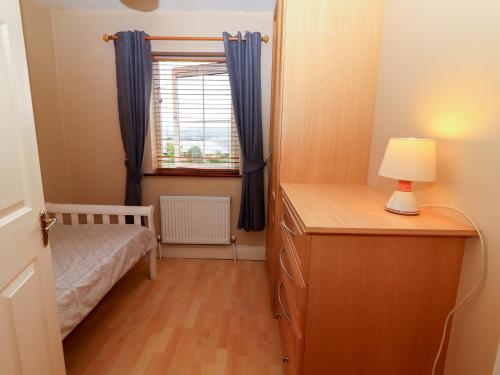 a bedroom with a bed and a dresser with a lamp at 51 Woodview Park in Tralee