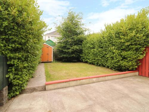 a garden with a red fence and bushes at 51 Woodview Park in Tralee