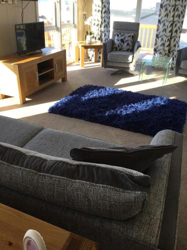 a living room with a couch and a blue rug at Rivendale Lodge in Burghead