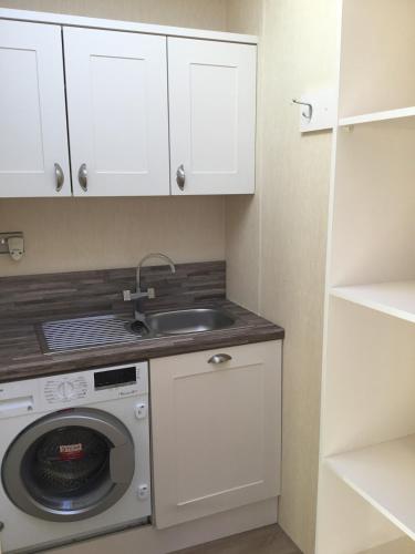 a kitchen with a sink and a washing machine at Rivendale Lodge in Burghead