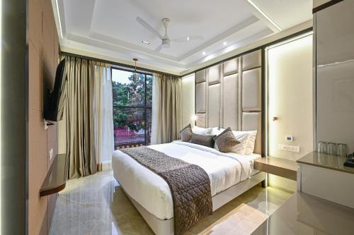 a bedroom with a large bed and a window at Hotel Grand Girdhar Premier in Indore