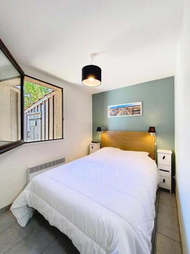 une chambre avec un lit blanc et une fenêtre dans l'établissement Résidence Maisons De La ForÊt - Maisonnette 4 pers, forêt, Lacanau Océan MAE-0431, à Lacanau