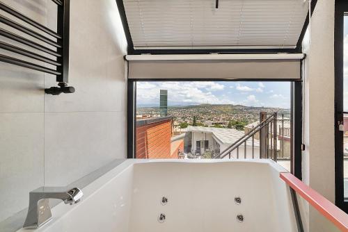 una vasca bianca in un bagno con finestra di PREMIUM APARTMENTS WITH TERRACE IN OLD TBiLISI a Tbilisi City