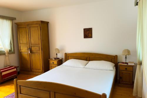a bedroom with a bed with white sheets and wooden furniture at Locul cu Amintiri in Albac