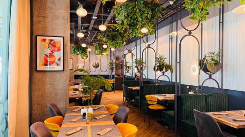 Your Home in Bucharest - Premium 1BR Apartments in ONE Cotroceni في بوخارست: مطعم بطاولات خشبية وكراسي ونباتات