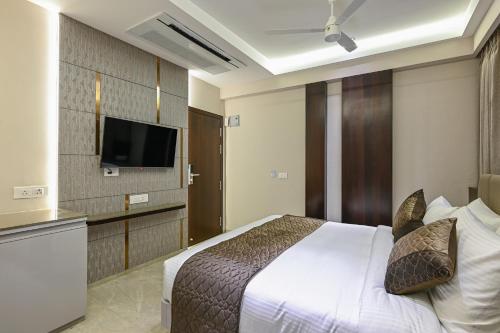 a bedroom with a bed and a flat screen tv at Hotel Grand Girdhar Premier in Indore