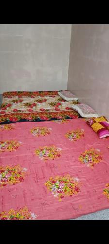 a bed with a pink blanket with flowers on it at Babu vishwanath singh Paying Guesthouse in Varanasi